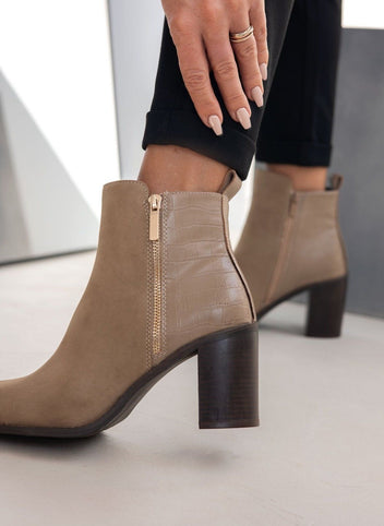 Taupe suede ankle boot with croc-embossed panel, gold side zip and block heel, worn on model, side view