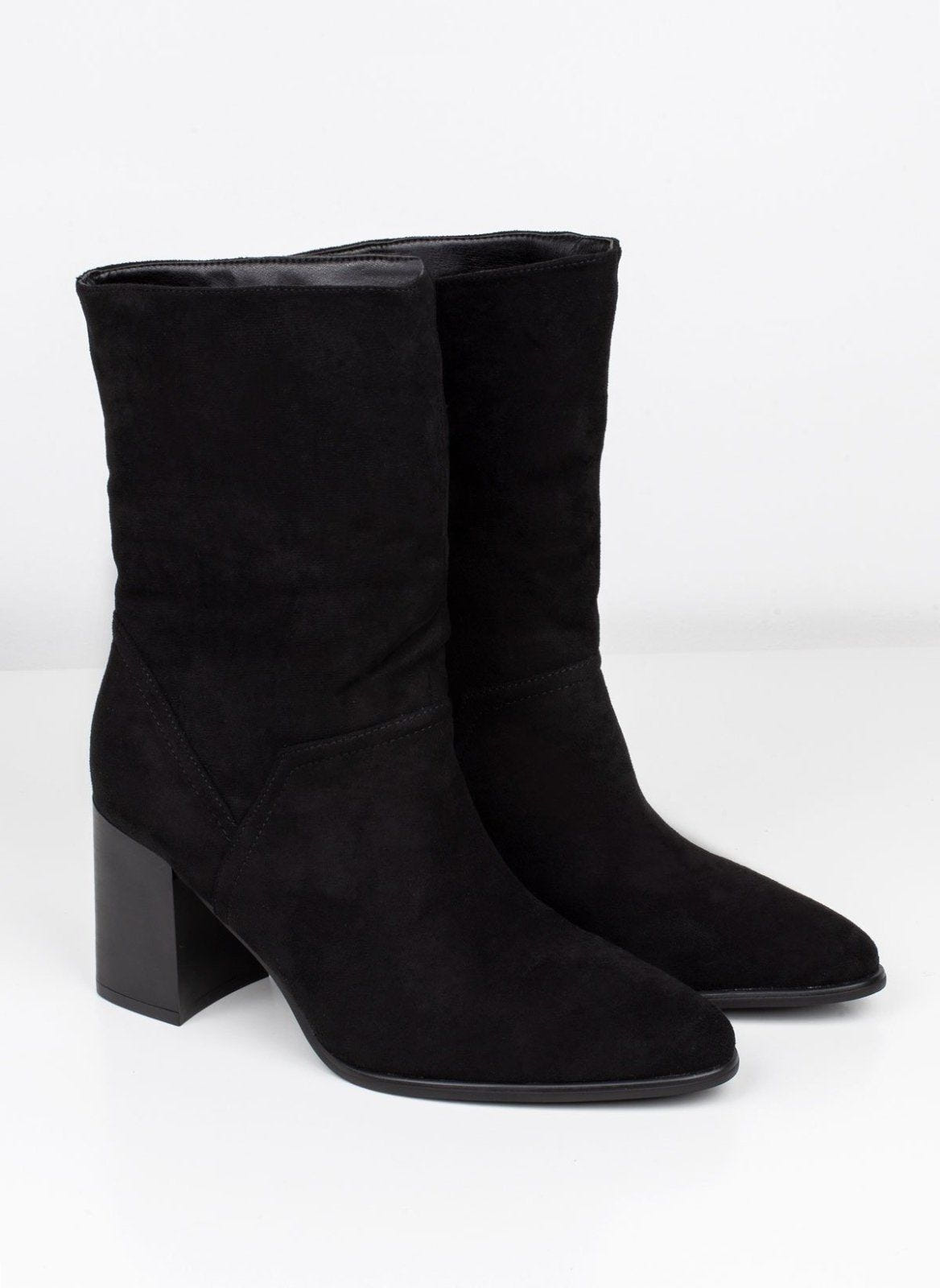 Pair of black suede block heel ankle boots with pointed toe and slouchy shaft on white background