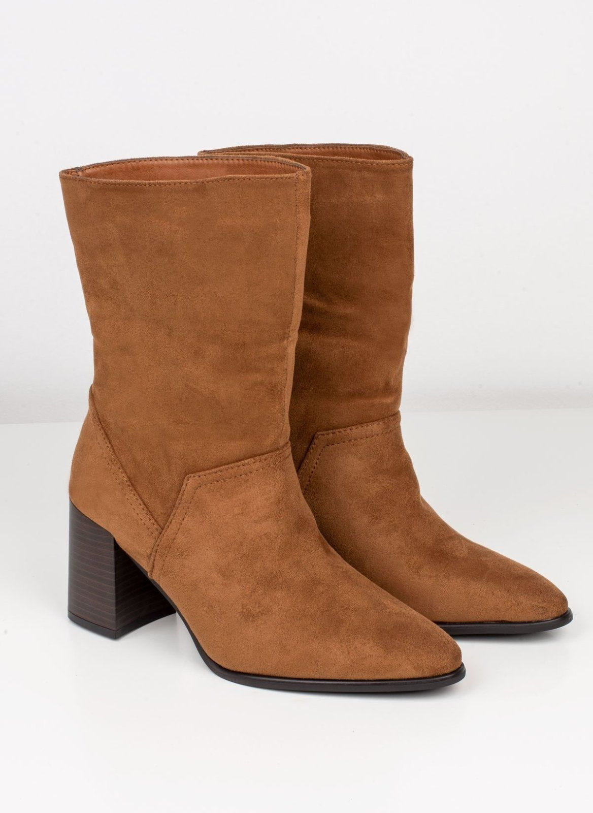 Pair of tan suede block heel ankle boots with pointed toe and slouchy shaft on white background