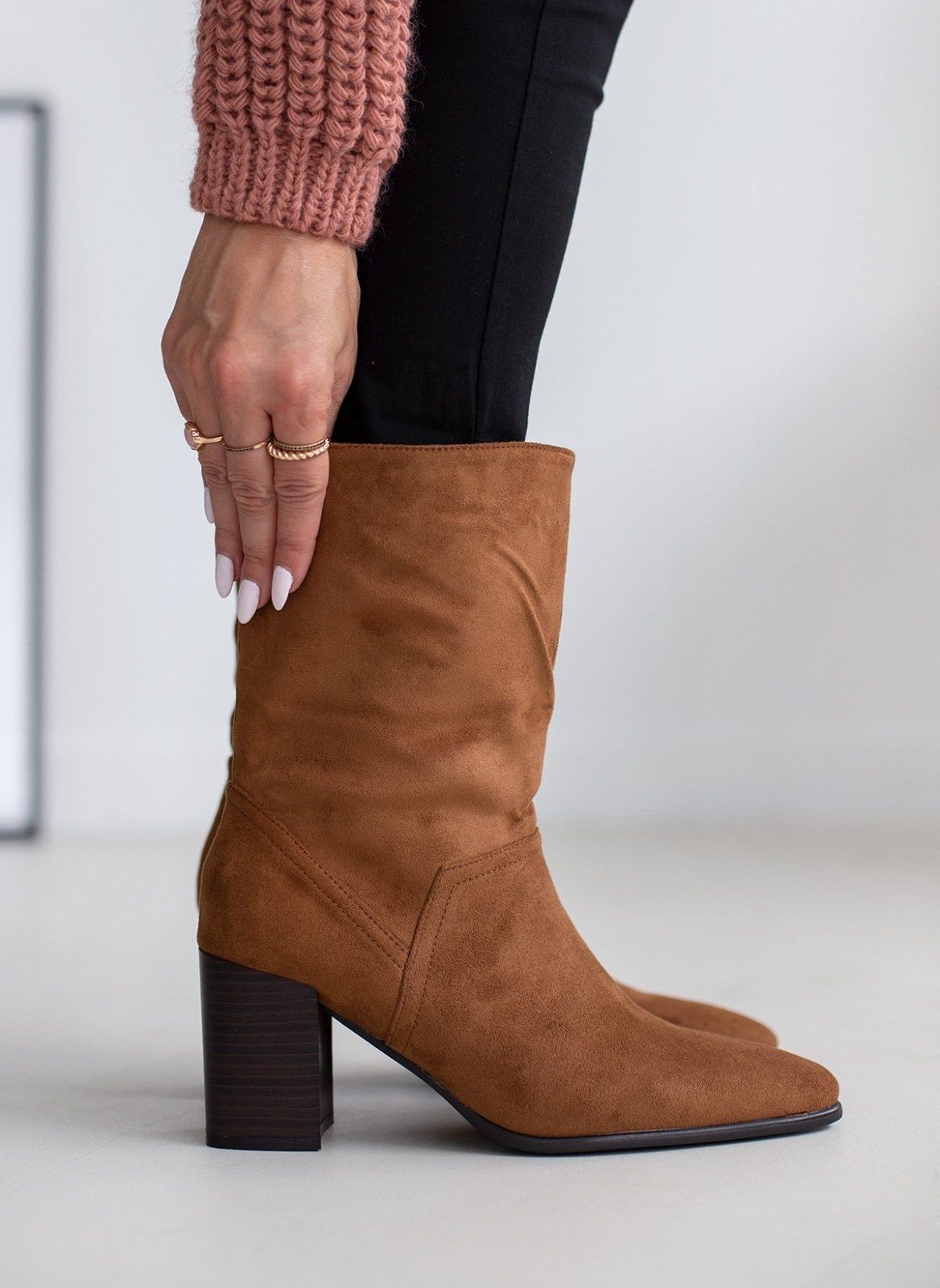 Tan suede block heel ankle boot worn on model, front view while model adjusts shaft