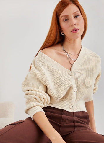Cream chunky knit V neck button cardigan with knit detail, close-up of model seated, front view