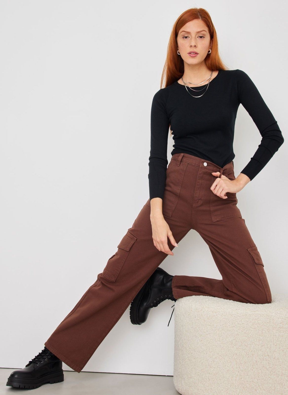 Brown wide leg cargo pants with high waist and side pockets, front view on model posing seated