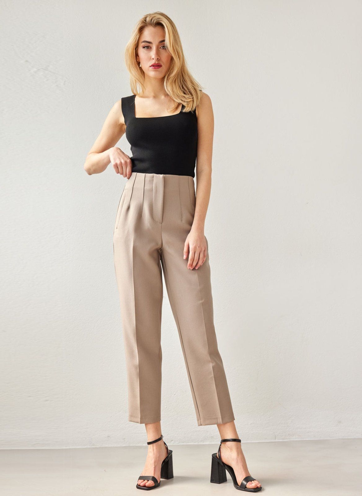Taupe high-waisted tapered chino trousers with pleated front and pressed crease, worn on model, full-length front view