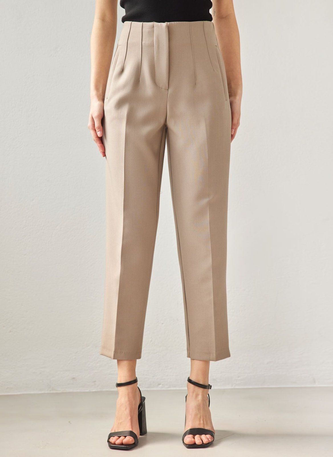 Taupe high-waisted tapered chino trousers with front pleats, zip fly and cropped ankle hem, worn on model, front view