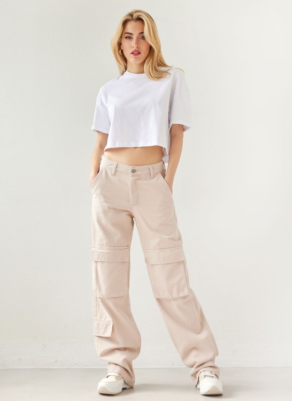 Beige baggy cargo denim pants with large thigh and knee pockets, full length front view on model