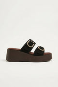 Black suede platform sandal with two straps and gold buckle on thick dark brown sole, side view on light grey