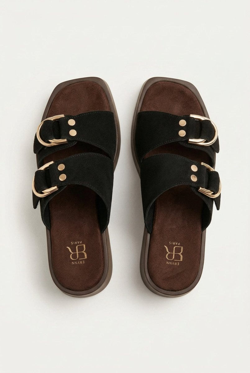 Top view of black suede straps with gold ring buckles and studs over a brown footbed and square toe