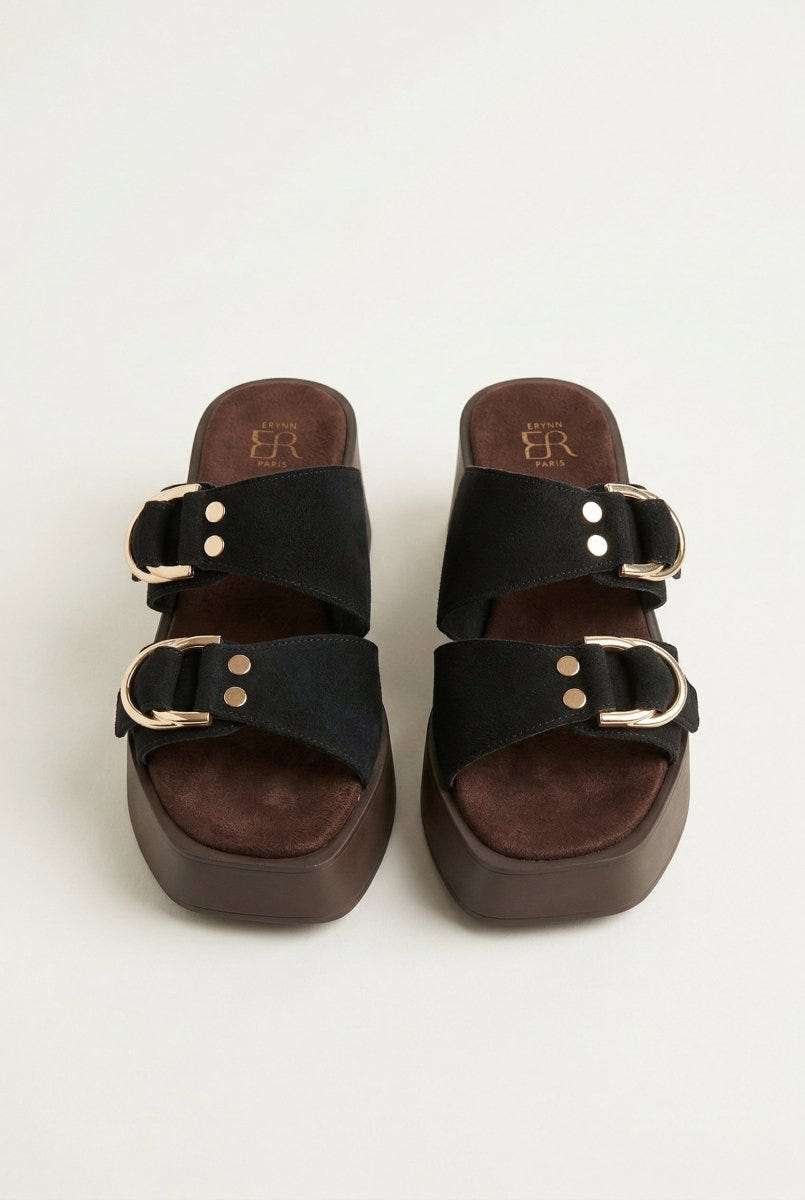 Front view of black suede platform sandals with gold rivet and buckle straps over a dark brown sole