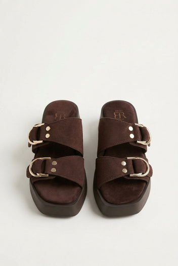 Pair of brown suede platform sandals with gold ring buckles and rivets, seen from the front showing square toes