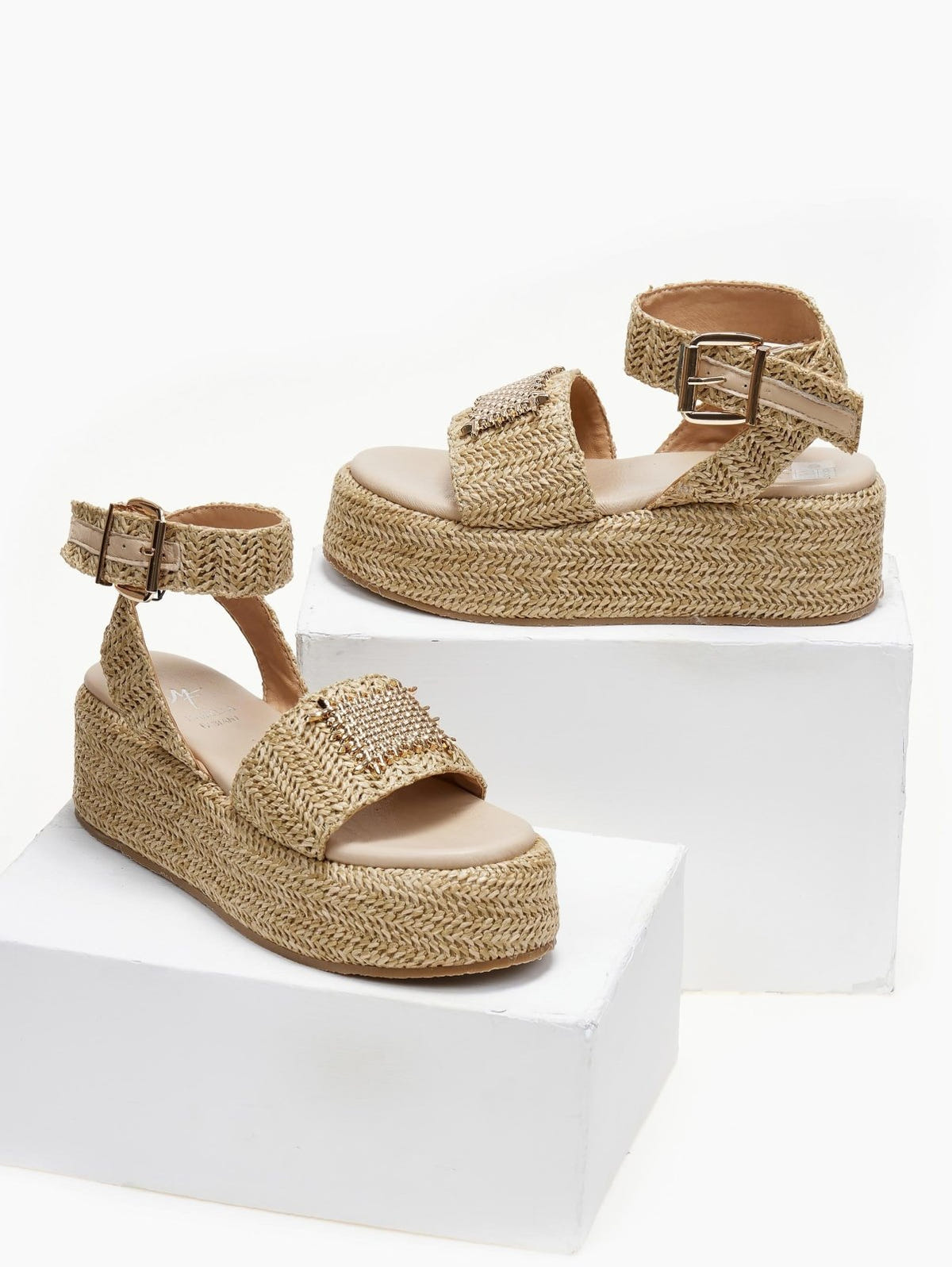 Pair of natural raffia platform sandals with ankle buckle strap and gold mesh detail, on white blocks