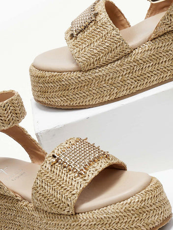Close-up of natural raffia platform sandal with gold mesh patch on the wide strap and ankle strap