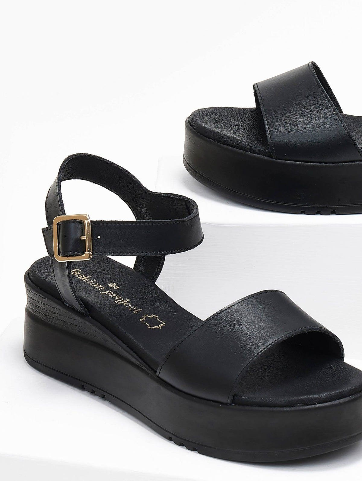 Close-up of black leather flatform sandal with ankle buckle strap and wide front strap