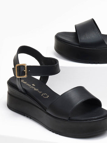 Close-up of black leather flatform sandal with ankle buckle strap and wide front strap