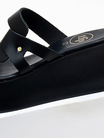 Close-up of black leather platform slide sandal with crossover strap and gold stud detail