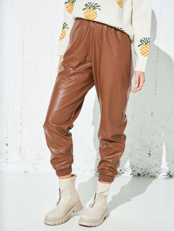 Brown faux leather jogger pants with elasticated waist and gathered elastic ankle cuffs, relaxed fit, worn on model, front view