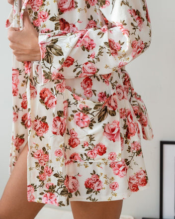 White velvet robe with pink rose floral print, patch pocket, wide cuffed sleeve and tie belt, worn on model, close-up of side and pocket