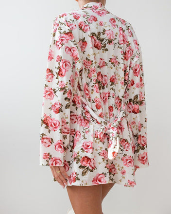 White velvet robe with pink and red rose floral print, wide sleeves and knotted tie belt at the waist, worn on model, back view