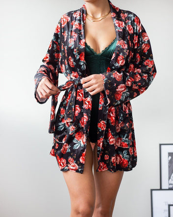 Black velvet robe with red rose floral print, wide sleeve and belt tied in front, worn on model, front view