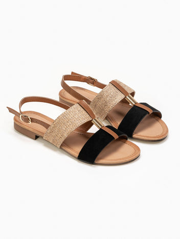 Pair of flat sandals with woven straw and black suede straps, tan leather ankle strap with gold buckle and low heel, front three-quarter on white