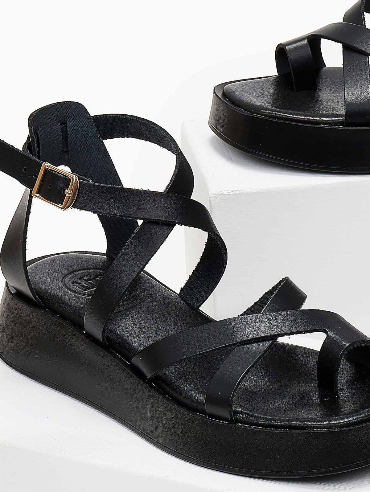 Close-up of black leather crossover strap platform sandal with toe loop and ankle buckle