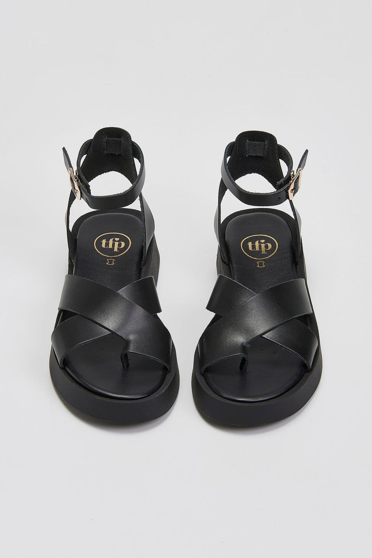 Pair of black leather crossover strap platform sandals with ankle buckle straps, top view
