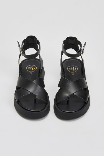 Pair of black leather crossover strap platform sandals with ankle buckle straps, top view