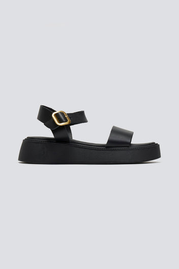 Black leather platform sandal with wide front strap and gold ankle buckle, side profile view