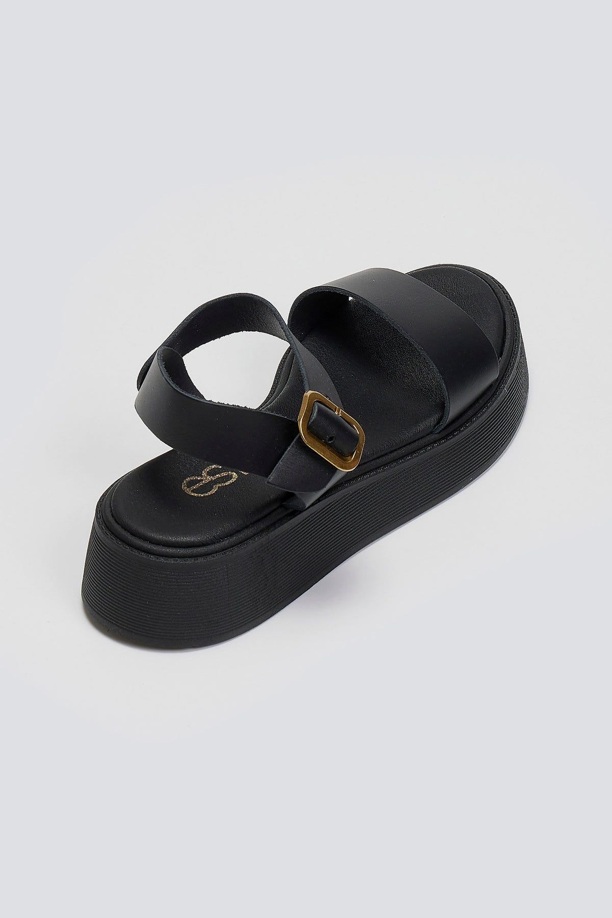 Black leather platform sandal with wide front strap and gold ankle buckle, back three-quarter view