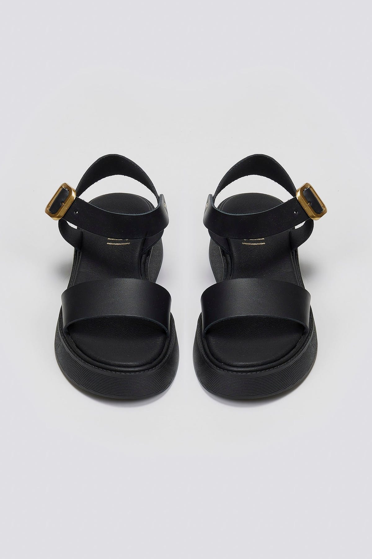 Pair of black leather platform sandals with wide front strap and gold ankle buckle, front view