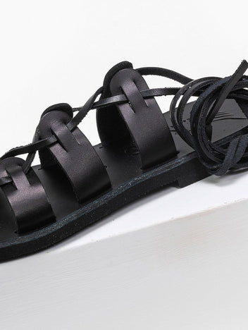 Close-up of black leather lace-up flat sandal with toe loop and wrapped ankle ties