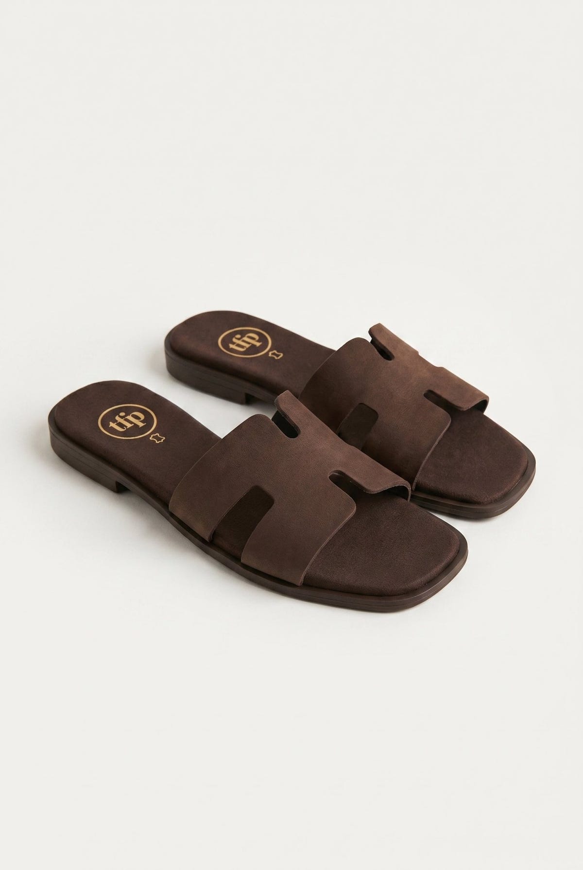 Pair of dark brown suede cut-out H strap flat slide sandals with square toe, three-quarter view