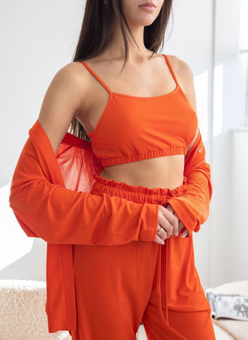 Close-up of orange ribbed pyjama camisole top with thin straps and elasticated hem, worn on model
