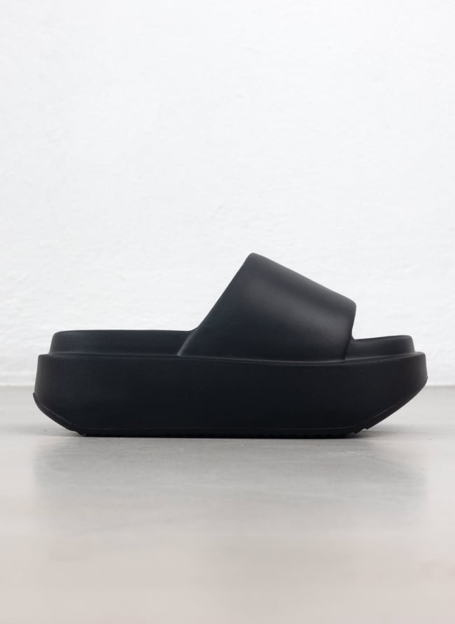 Black matte platform slide sandal with wide padded strap and thick sole, side view