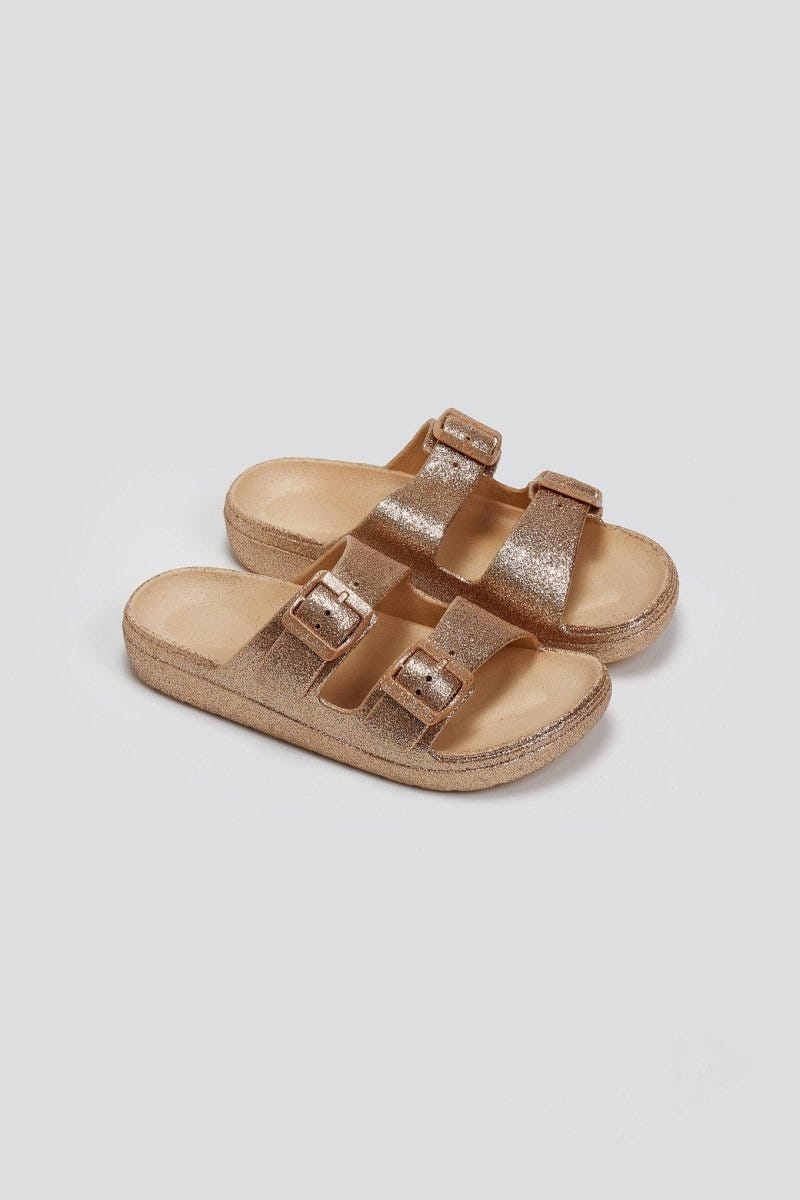 Pair of rose gold glitter double buckle slide sandals with beige footbed, three-quarter view