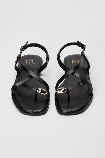Pair of black leather toe ring sandals seen from above with crossed straps and gold rings at the toes