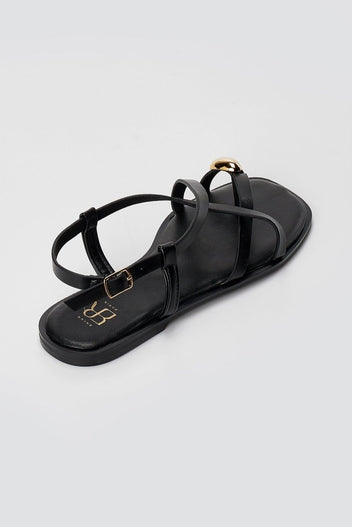 Single black leather toe ring sandal from above with crossed straps, gold ring at toe and a black padded footbed