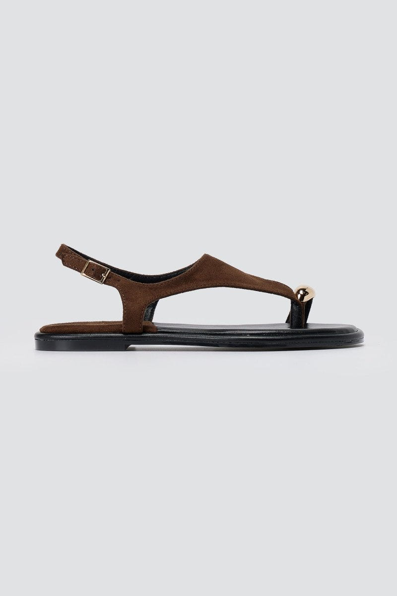 Single brown suede thong sandal in side view with a slim ankle strap, thin black sole and a small metal detail