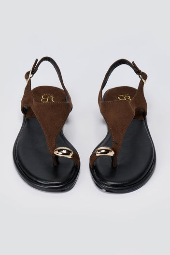 Pair of brown suede thong sandals with black soles and a round gold tone ornament, top view with ankle straps open